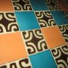 An image showing hand-made Tortuga Tiles featuring a Polynesian pattern in brown and cream set into a checkerboard of plain orange and turquoise tiles. 6" square.